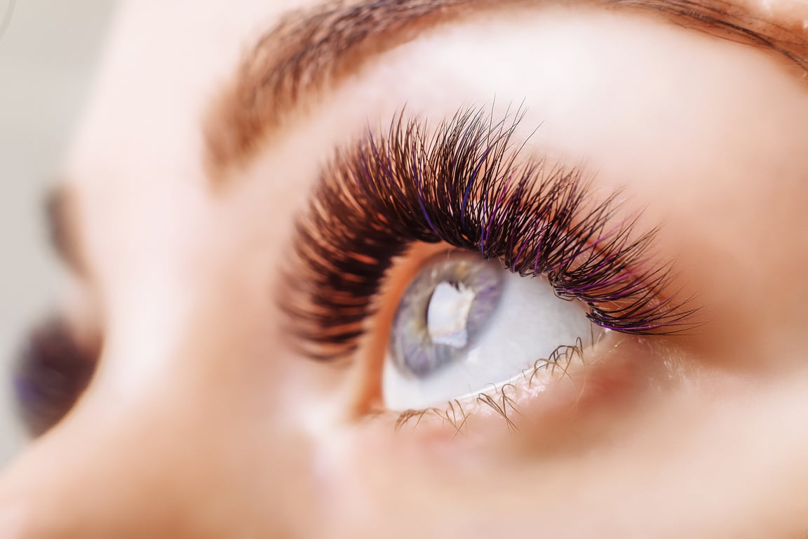 Eyelash Extension Procedure. Woman Eye with Long Eyelashes. Close up, selective focus